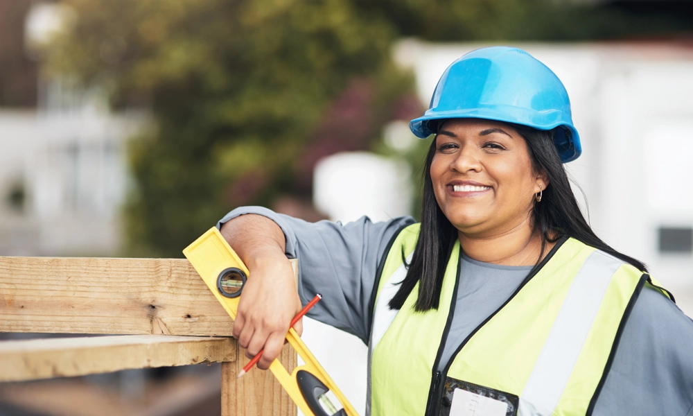 Person with a hard hat and a lever posing next to a wooden frame