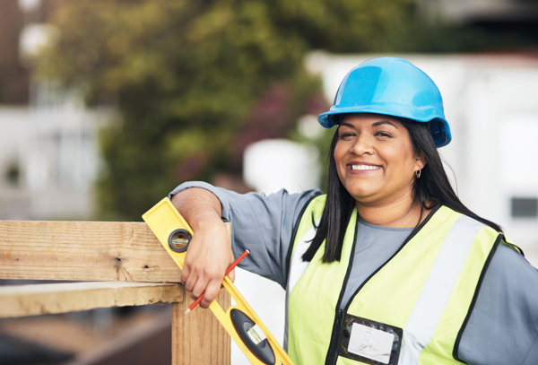 Person with a hard hat and a lever posing next to a wooden frame