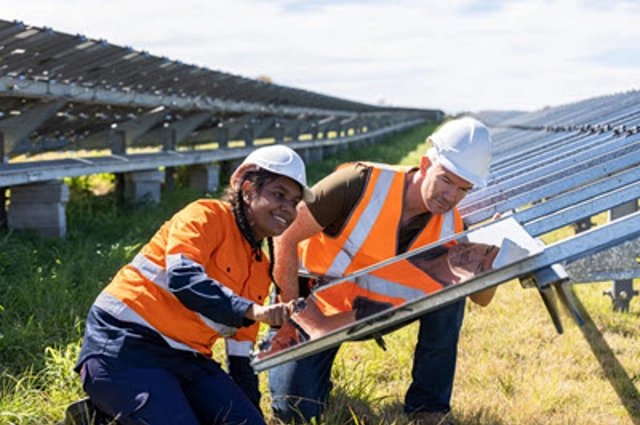One woman and one man installing solar panels in a field