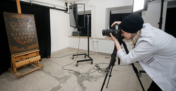 Person in a lab coat looking through the lens of a digital microscope 