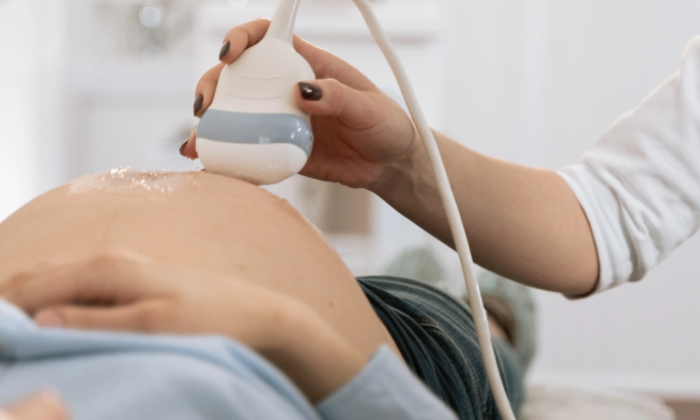 Pregnant person lying down with an ultrasound machine on her belly