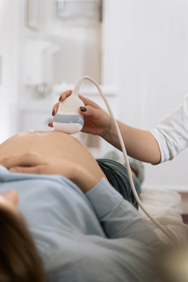 Pregnant person lying down with an ultrasound machine on her belly