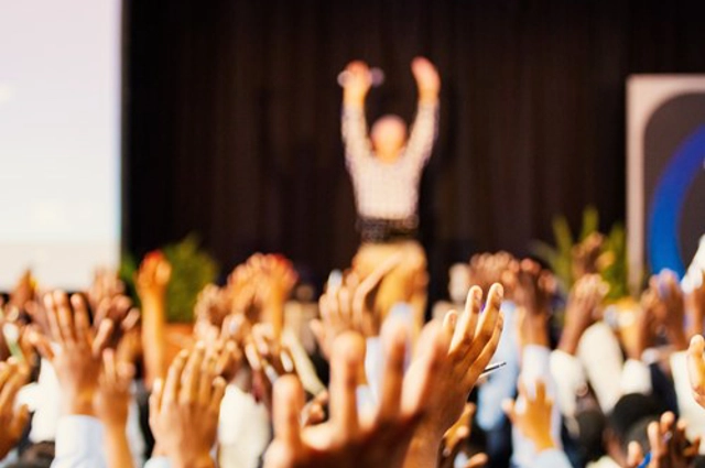 Audience members and presenter all with hands in air