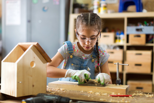 A girl is sanding a piece of wood