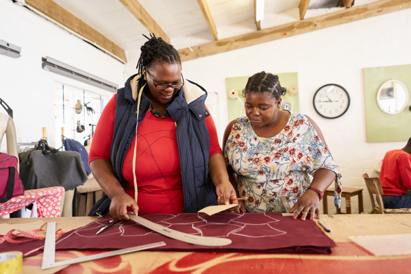 Two people cutting patterns on a fabric