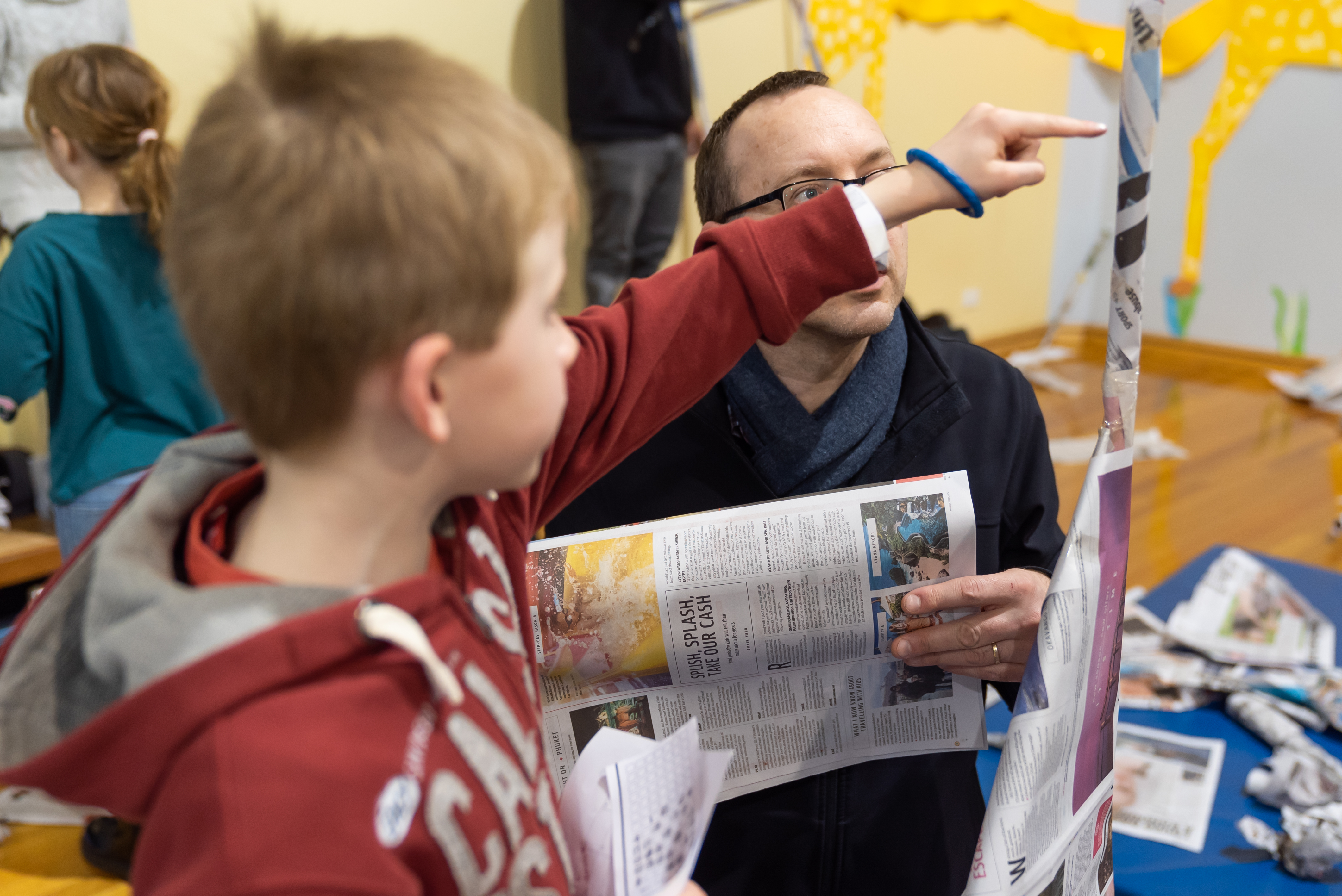 Primary school aged child pointing at newspaper structure 