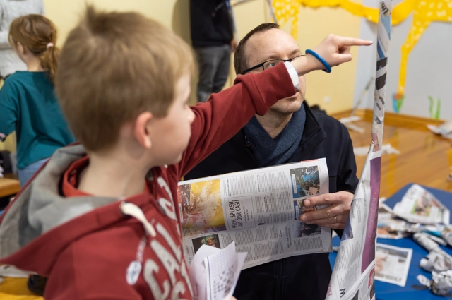 Primary school aged child pointing at newspaper structure