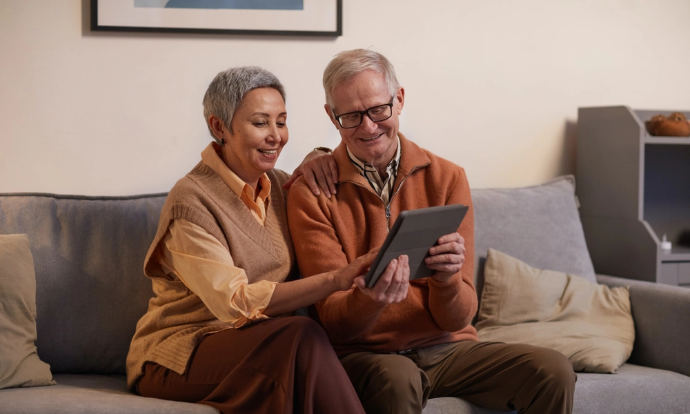 Elderly woman and man looking at a tablet while smiling