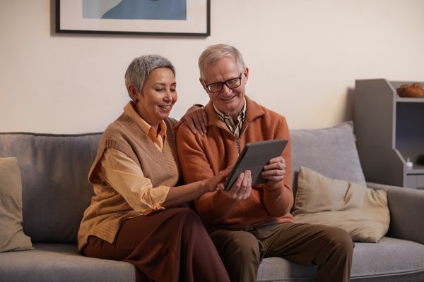 Elderly woman and man looking at a tablet while smiling