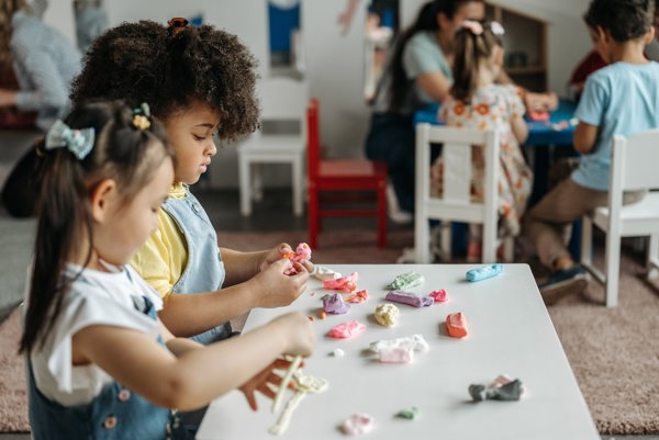 Two small children sculpting and playing with play doughs at a table