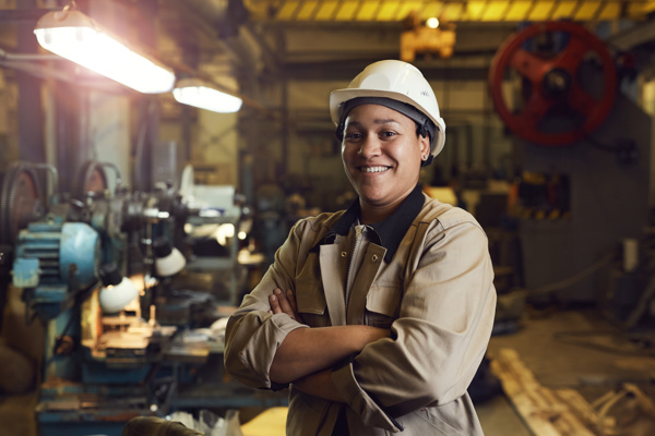 Person with a hard hat is posing in a manufacturing workshop