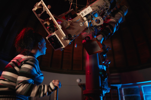 A woman is looking through a large telescope