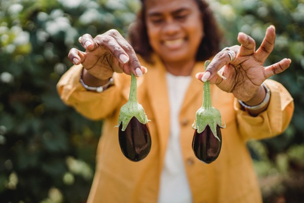 Person showing two small eggplants and smiling