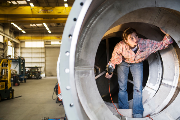 Person with a tool is standing inside a metal pipe