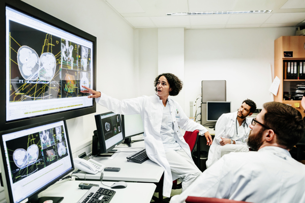 Three doctors looking at screens showing x-rays