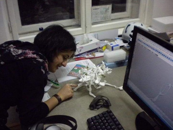 Person looking at a 3-d model next to a computer screen showing the same model