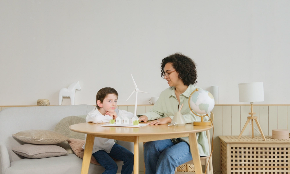 A woman and a boy sitting at the table looking at a windmill model