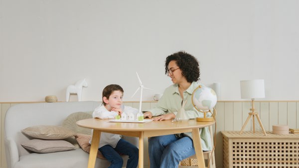 A woman and a boy sitting at the table looking at a windmill model