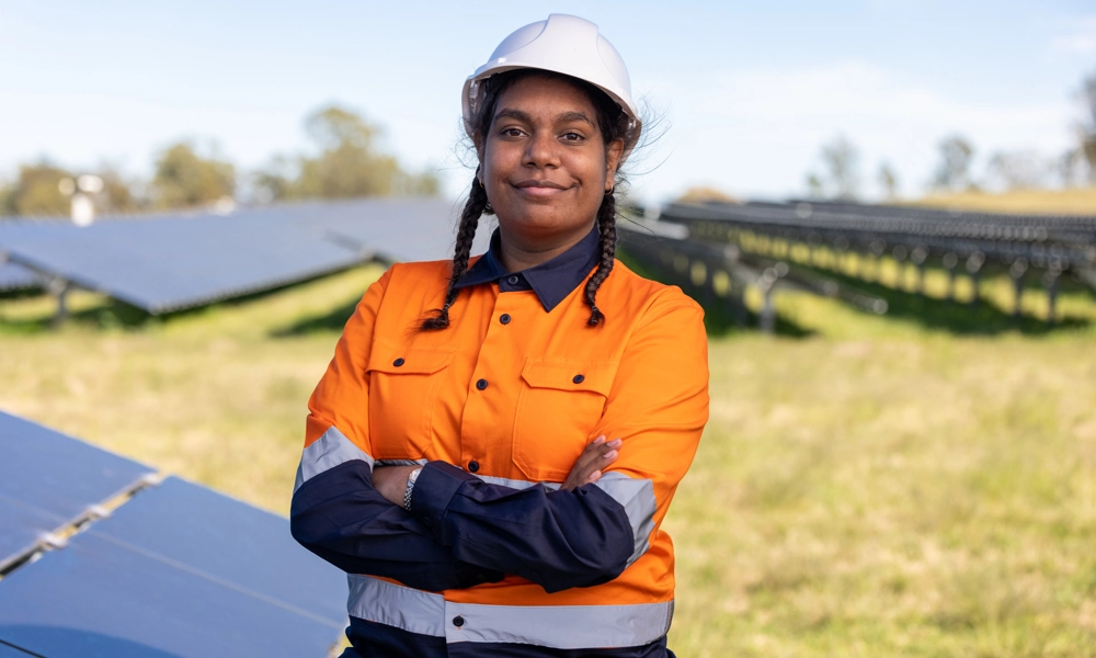 Person with a hard hat and high-vis work uniform is standing in a solar farm