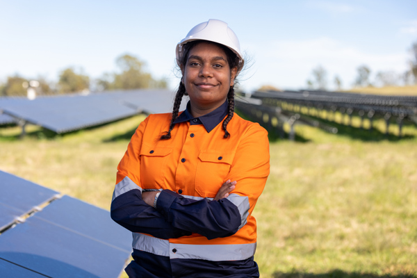Person with a hard hat and high-vis work uniform is standing in a solar farm