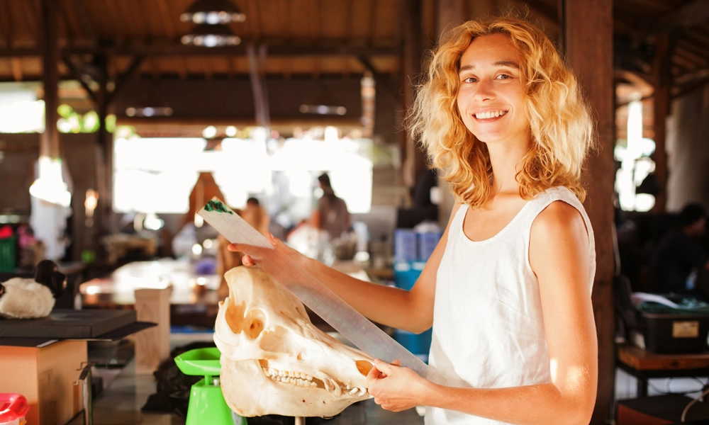 A woman is holding a big animal skull in her hand