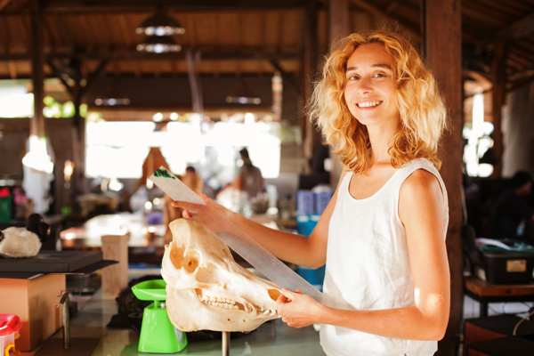 A woman is holding a big animal skull in her hand