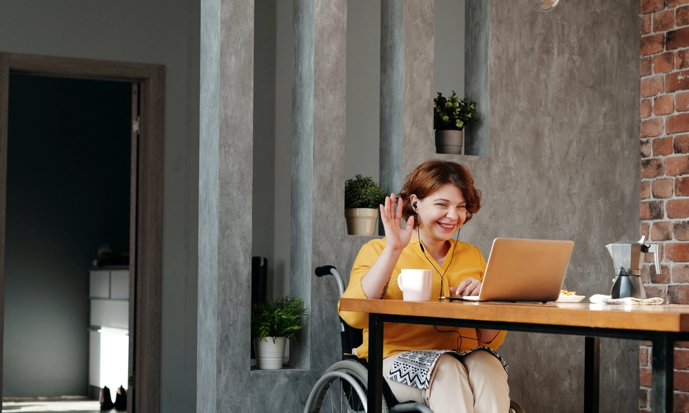 Person on a wheelchair waving at a computer
