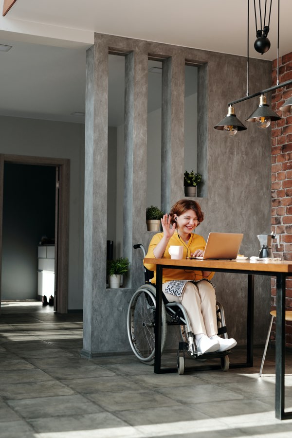 Person on a wheelchair waving at a computer