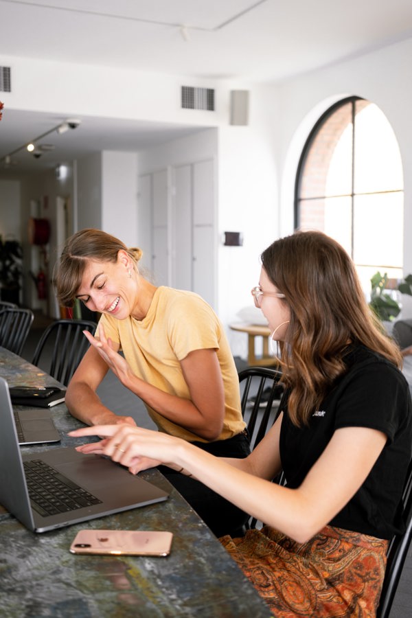 Two people laughing and pointing at a laptop screen