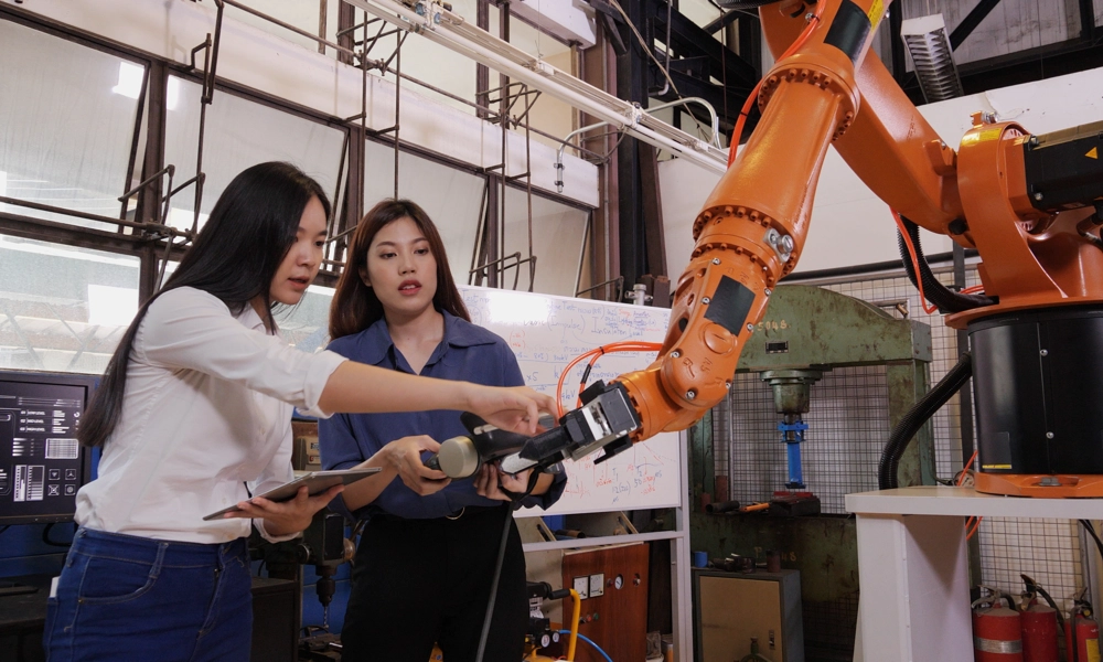 Two people working on a robotic arm