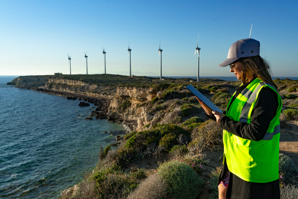 Person with a high-vis vest is standing next to wind turbines