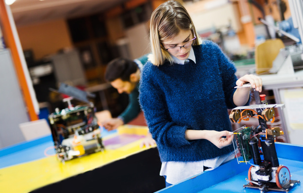 Two people working on building robots